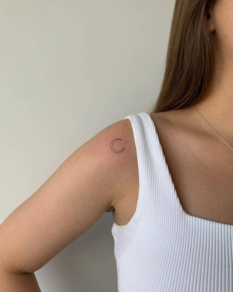 Fine line style crescent moon tattoo located on the shoulder.