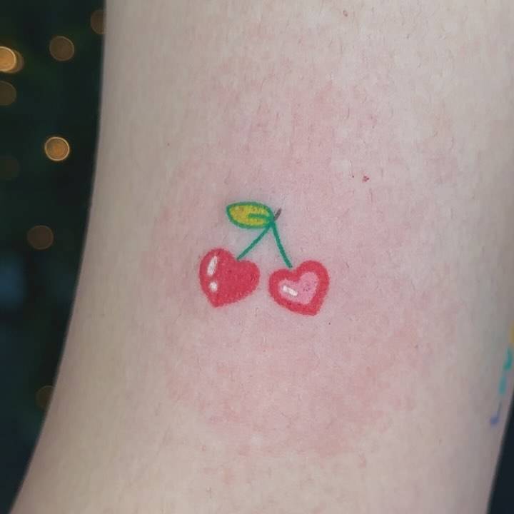 Hand poked cherry hearts tattoo located on the bicep.