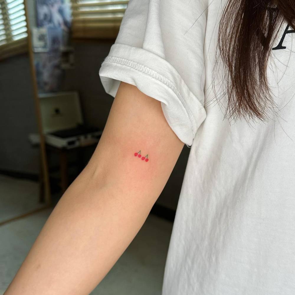 Minimalistic style tiny cherries tattooed on the inner arm.