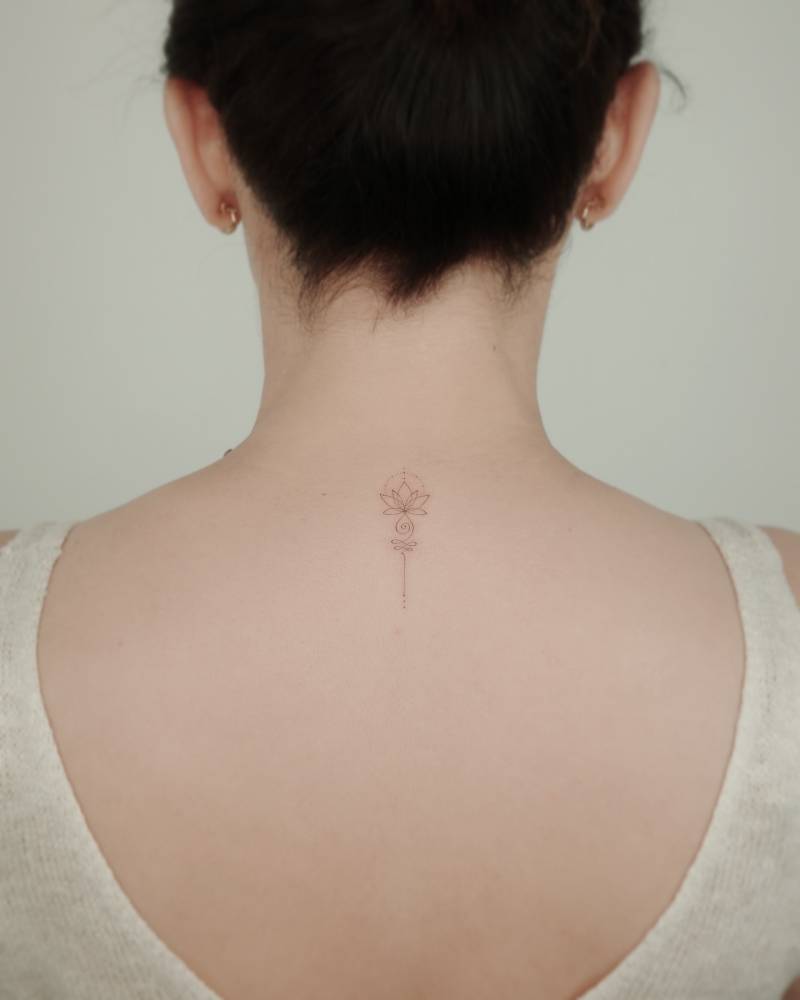 Lotus unalome tattoo in fine line style placed on the upper back.
