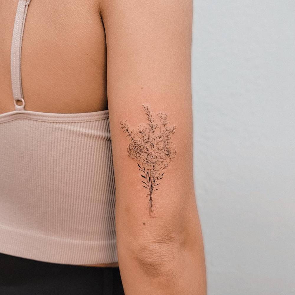 Fine line style flower bouquet tattoo located on the tricep.