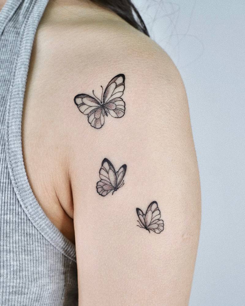 Butterflies tattoo located on the shoulder, illustrative style.