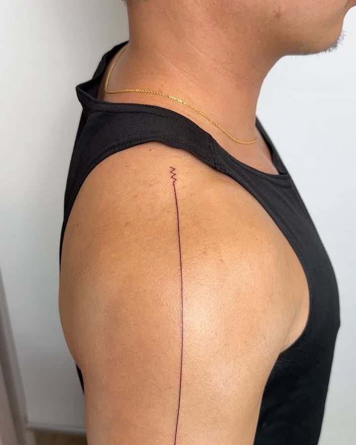 Minimalistic style line tattoo located on the shoulder.