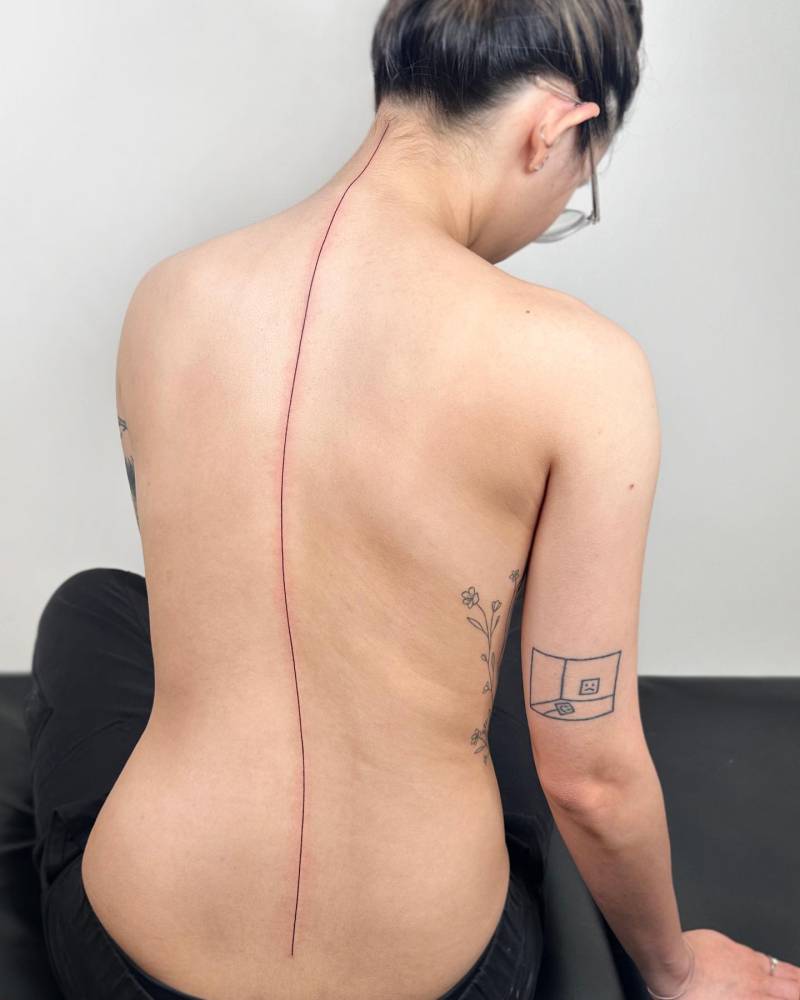 Minimalistic style line tattooed on the spine.