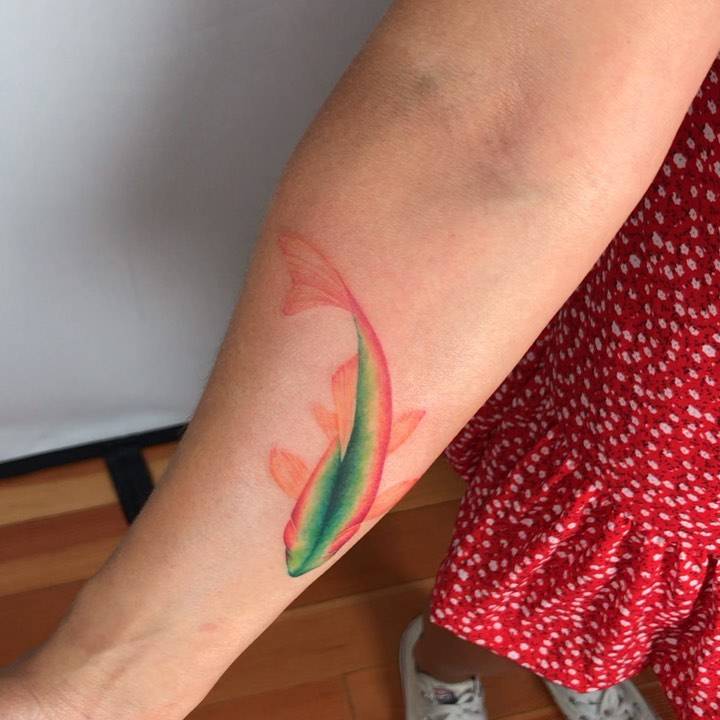 Colorful watercolor style koi fish tattoo located on the inner forearm.