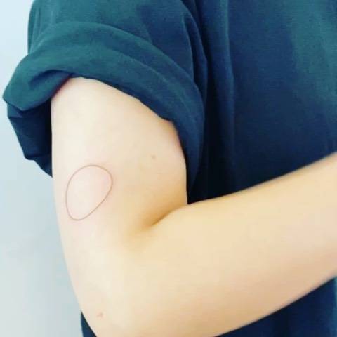 Circle tattoo placed on the upper arm, fine line style.