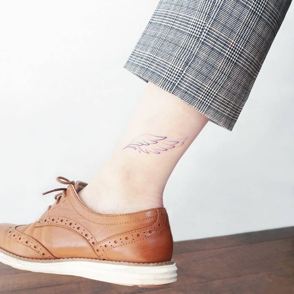 Watercolor style wings tattoo located on the ankle.