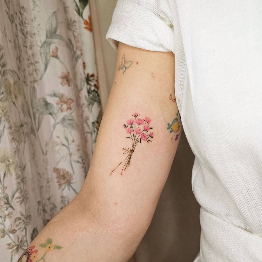 Pink peony bouquet tattoo in watercolor style located on the inner arm.