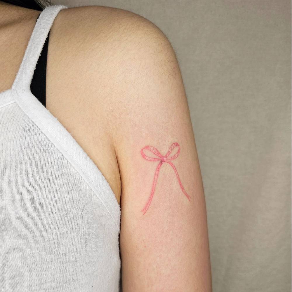 Ribbon tattoo in watercolor style located on the upper arm.