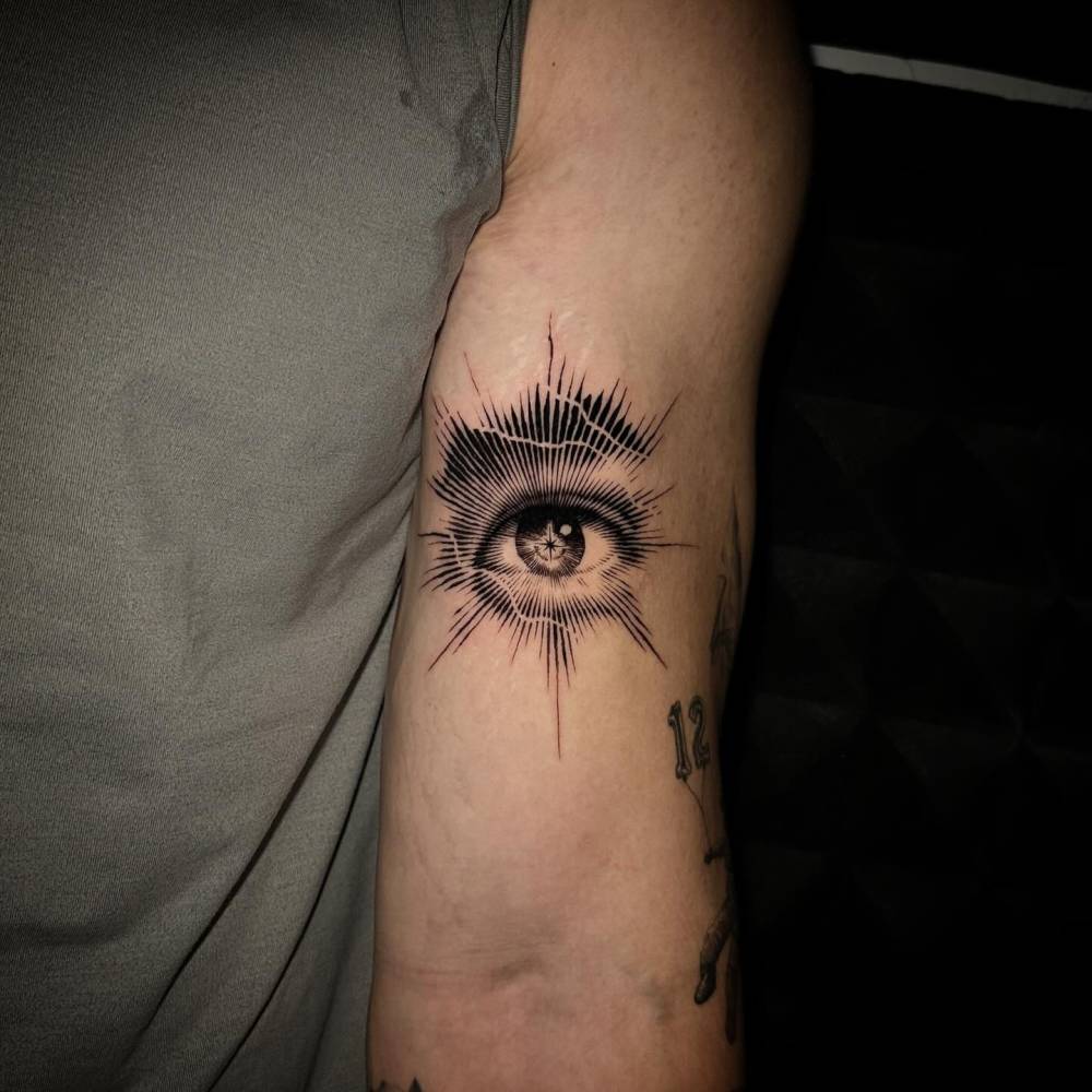 Eye tattoo located on the bicep, done in blackwork style.
