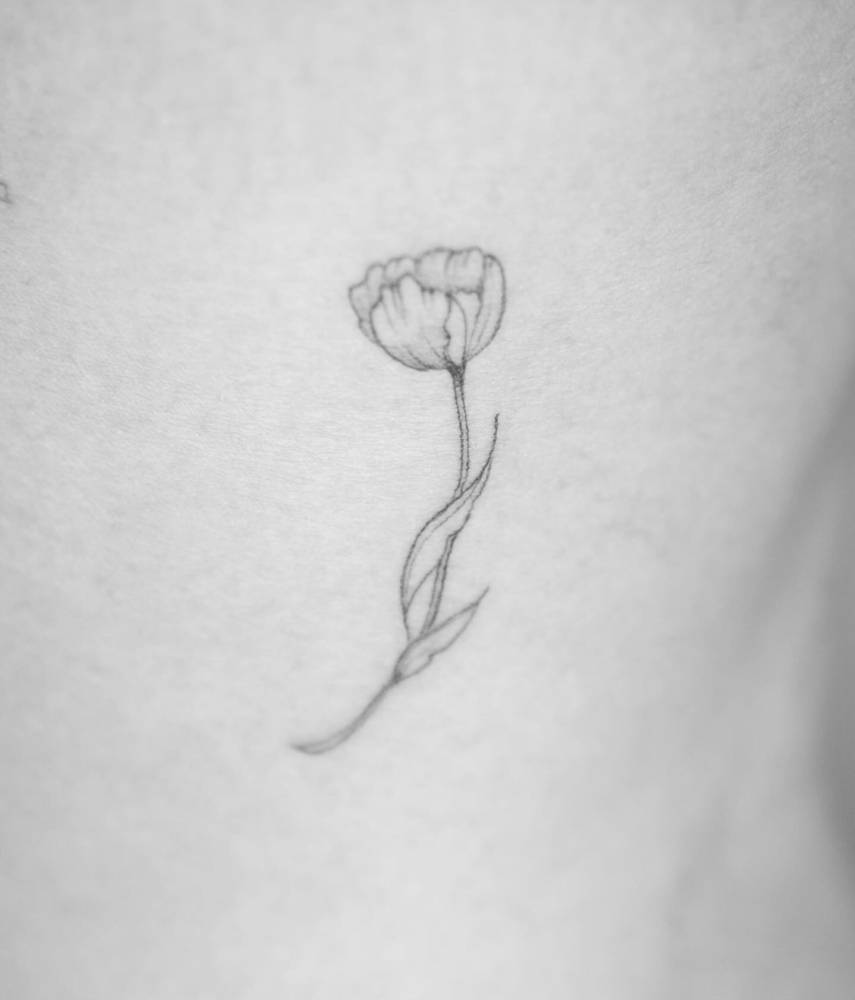 Fine line style tulip tattoo done on the thigh.