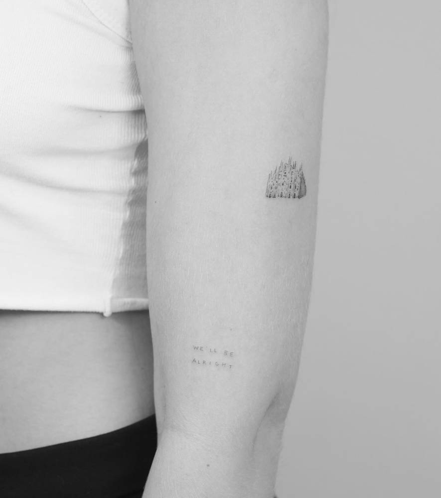 Duomo di Milano and "we'll be alright" tattoos located on the upper arm.