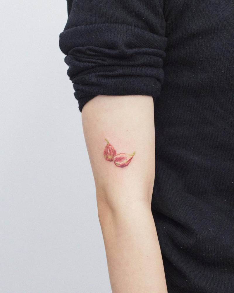 Figs tattooed on the upper arm, done in watercolor style.