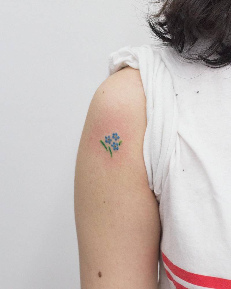 Forget-me-not tattoo located on the upper arm, watercolor style.