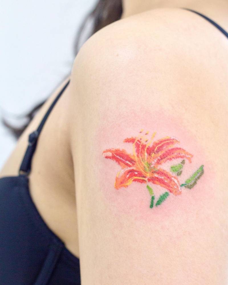 Crayon effect lily flower tattoo located on the upper arm.
