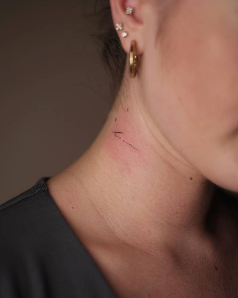 Handwritten lettering tattoo located on the neck.