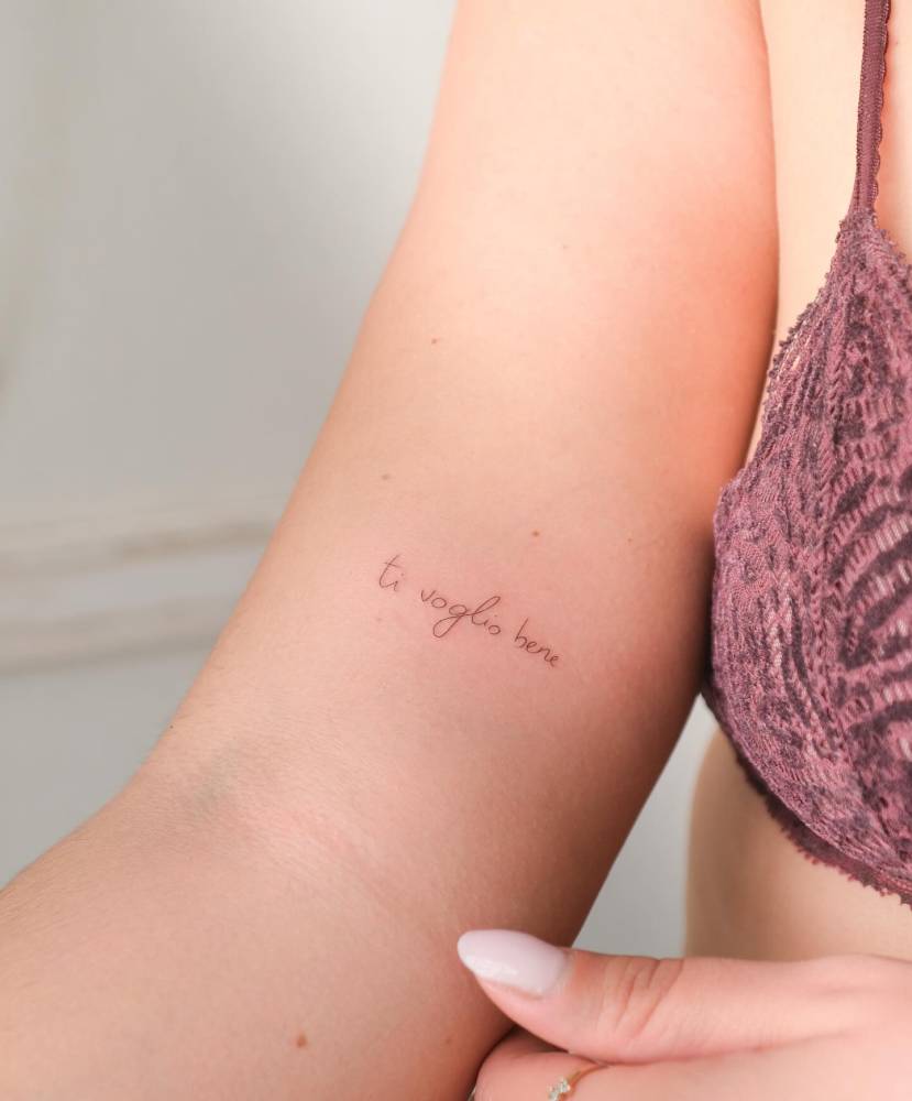 "Ti voglio bene" lettering tattoo handwritten on the bicep.