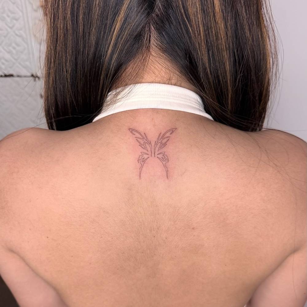Tribal butterfly tattoo in fine line style located on the upper back.