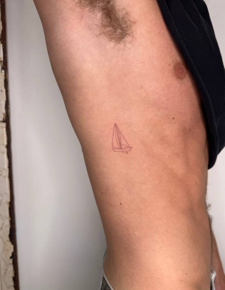 Sailboat tattoo located on the rib, done in fine line style.