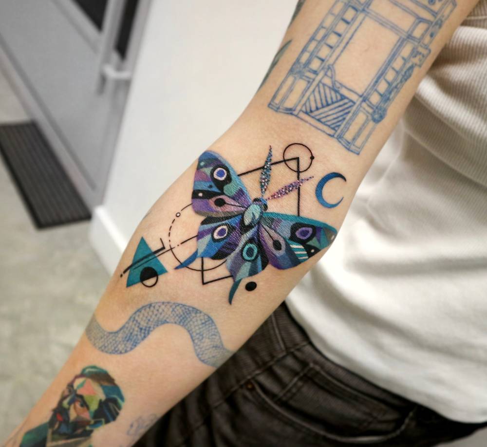 Graphic style moth tattooo located on the inner forearm.