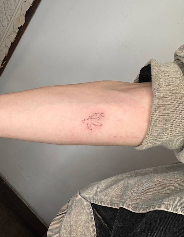 Little turtle tattoo located on the inner forearm, fine line style.