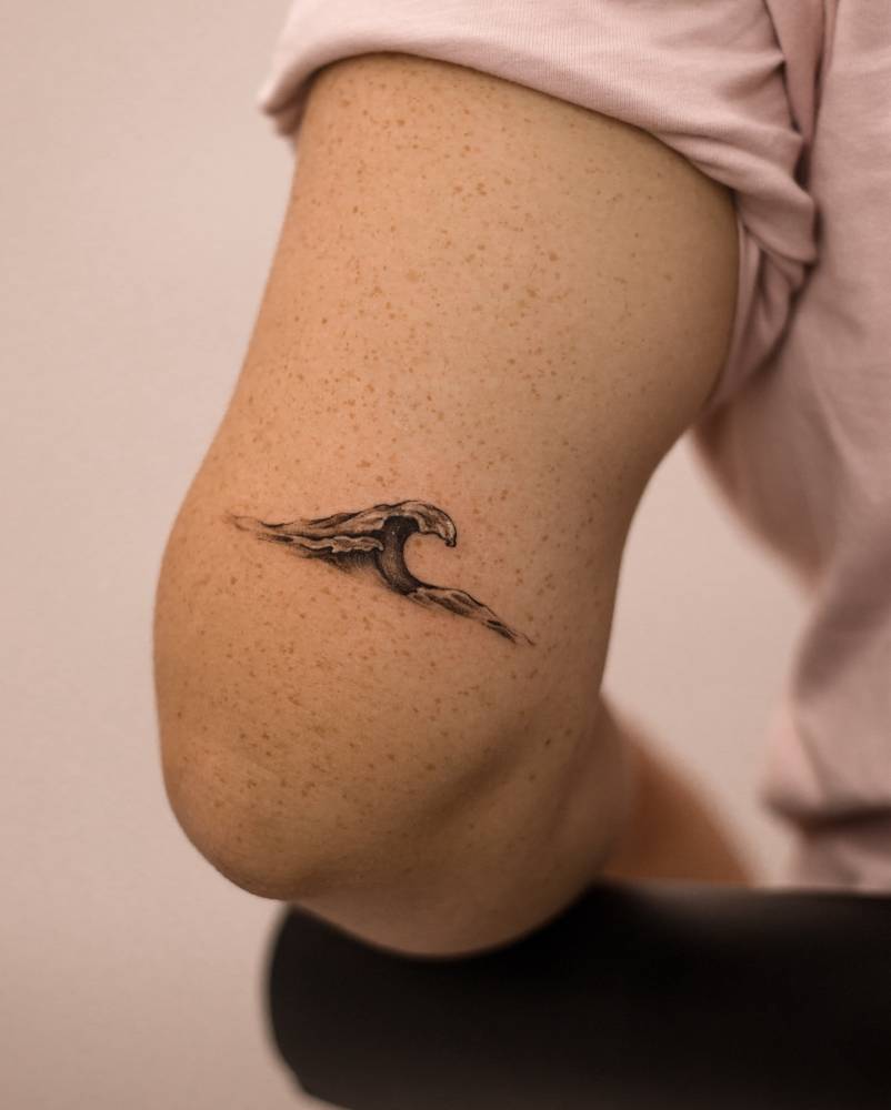 Micro-realistic style wave tattoo placed on the tricep.