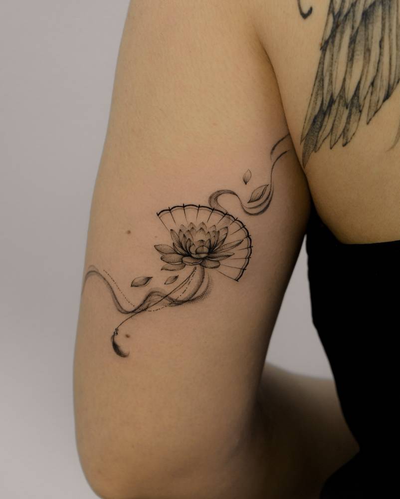Hand fan and lotus flower tattoo located on the tricep.
