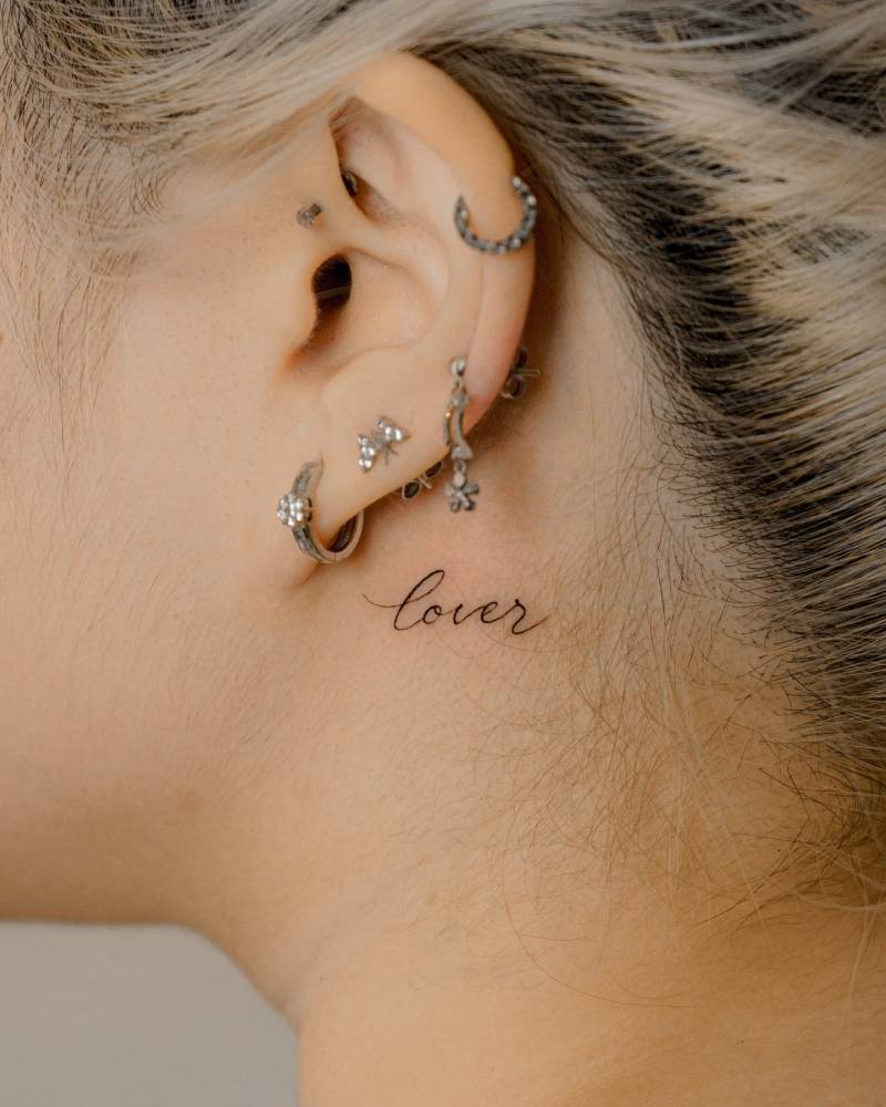 Lettering tattoo of the word "lover" in scrip font.