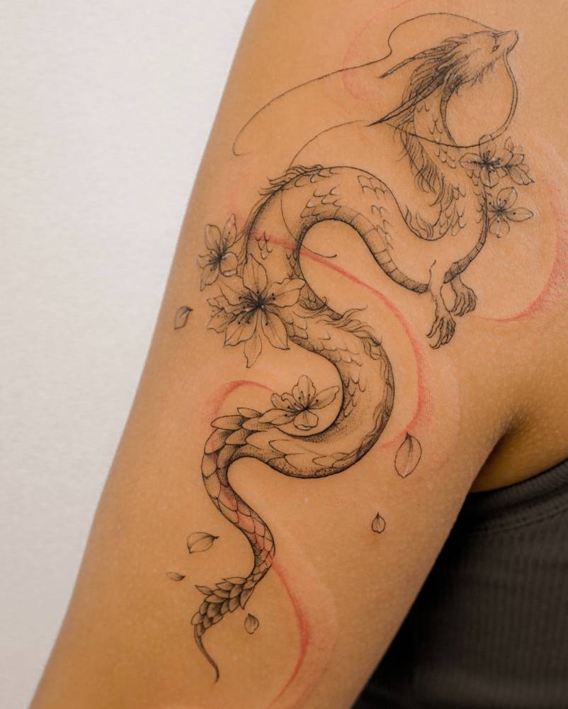 Illustrative style dragon tattoo placed on the upper arm.