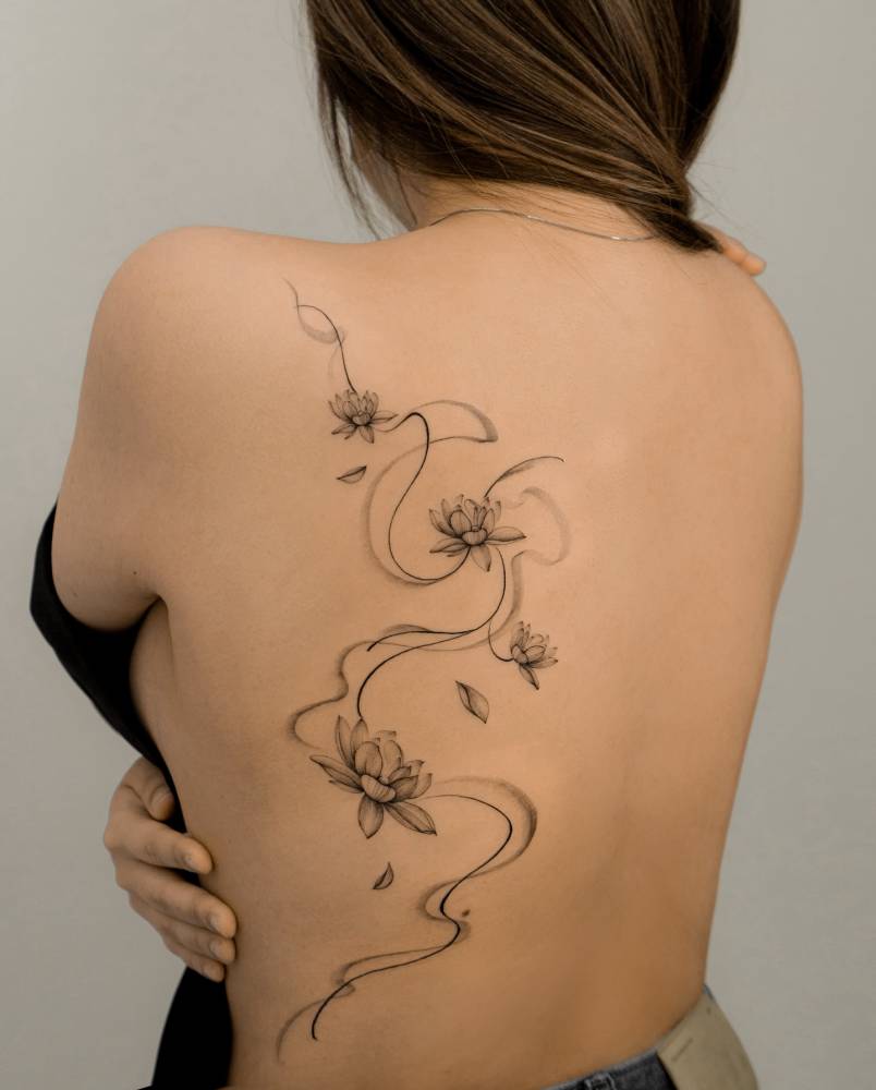 Lotus flowers tattooed on the back, done in illustrative style.