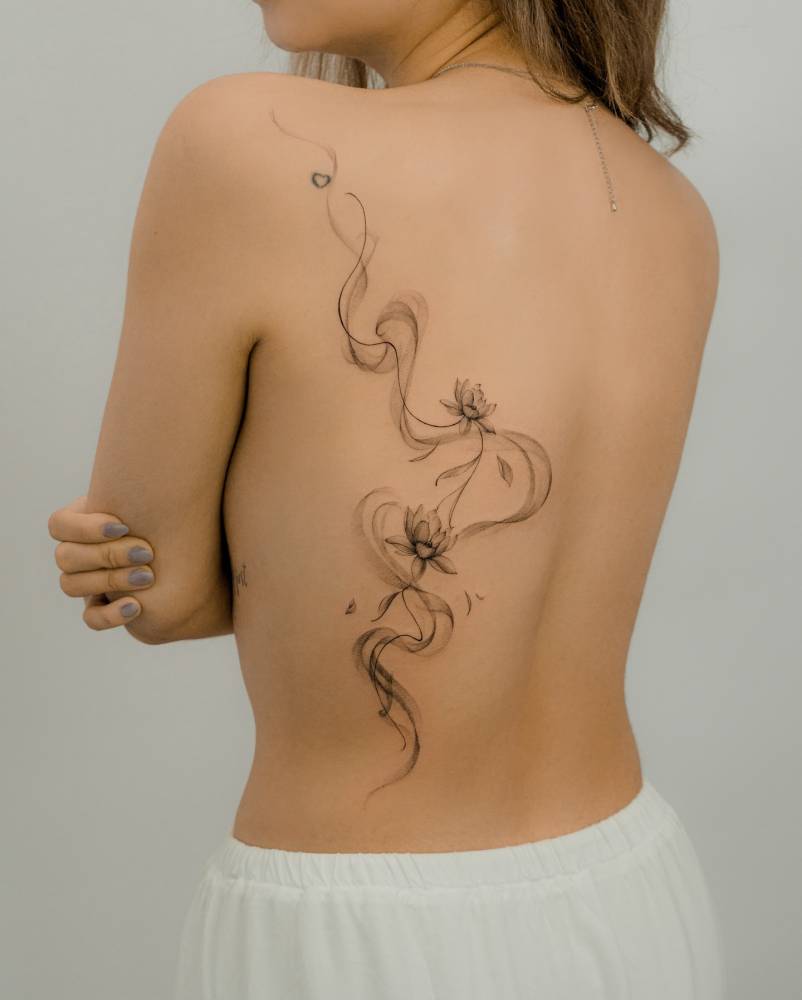 Lotus flowers tattooed on the back, done in illustrative style.