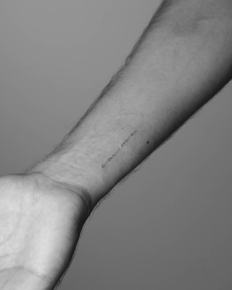 Handwritten font name "Emma" tattooed on the wrist.
