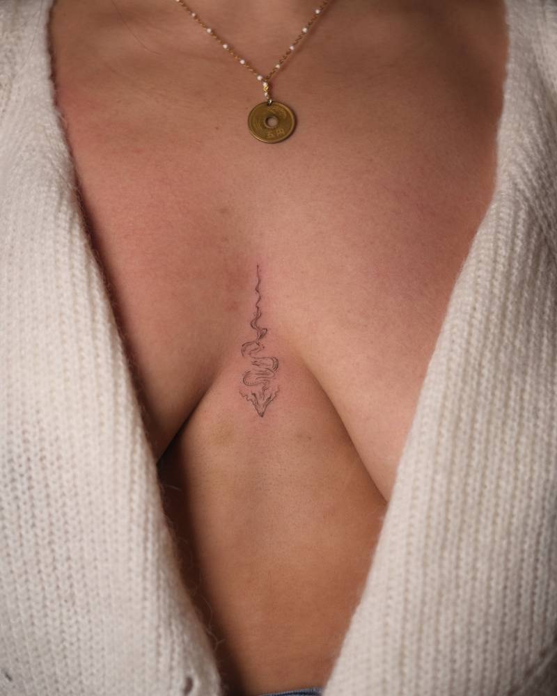 Small abstract dragon tattoo located on the sternum.