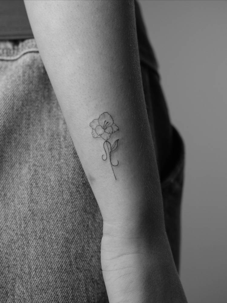 Gladiolus tattoo located on the wrist, fine line style.
