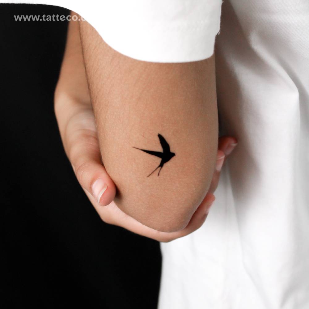 Black swallow semi-permanent tattoo located on the tricep.