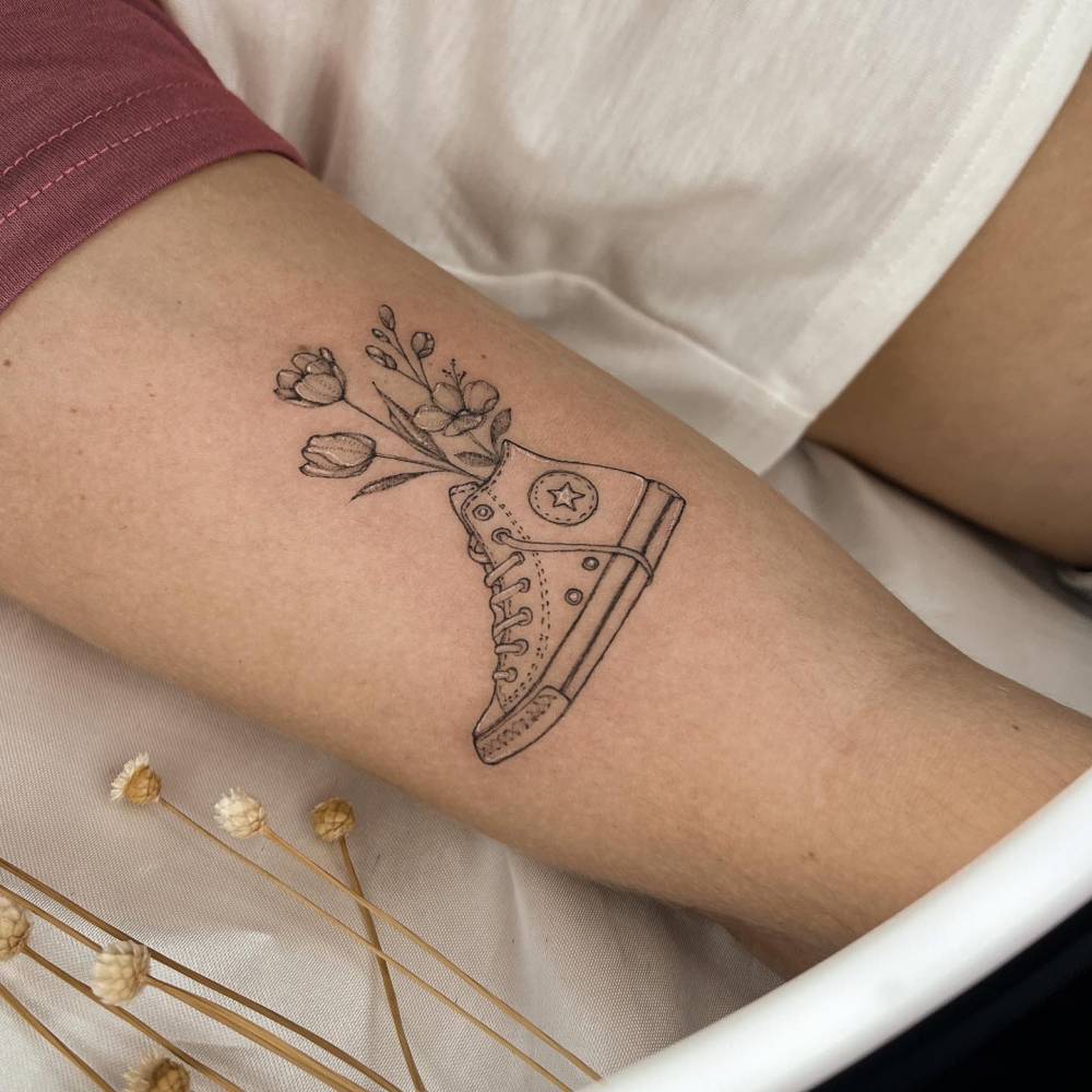 Converse All Star and flowers tattooed on the inner arm.