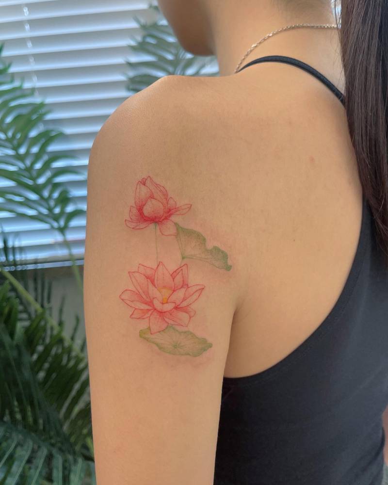 Watercolor style lotus flowers tattooed on the upper arm.