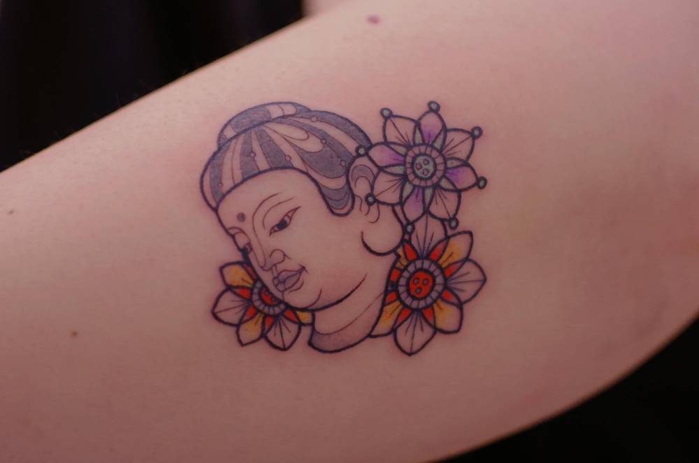 Buddha portrait tattoo in illustrative style done on the upper arm.