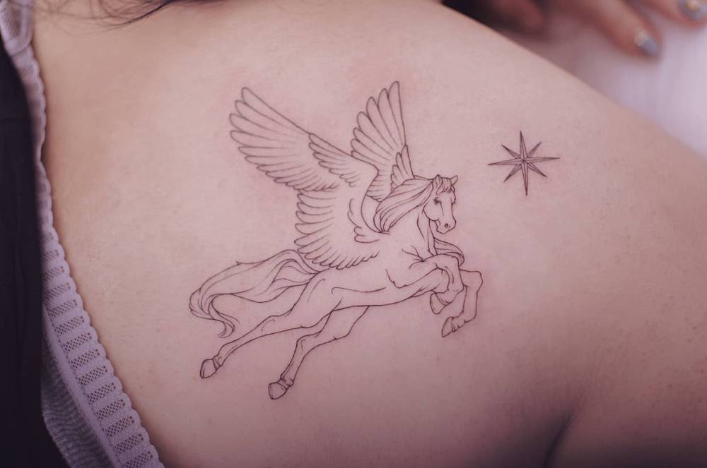 Pegasus tattoo located on the shoulder blade, done in fine line style.