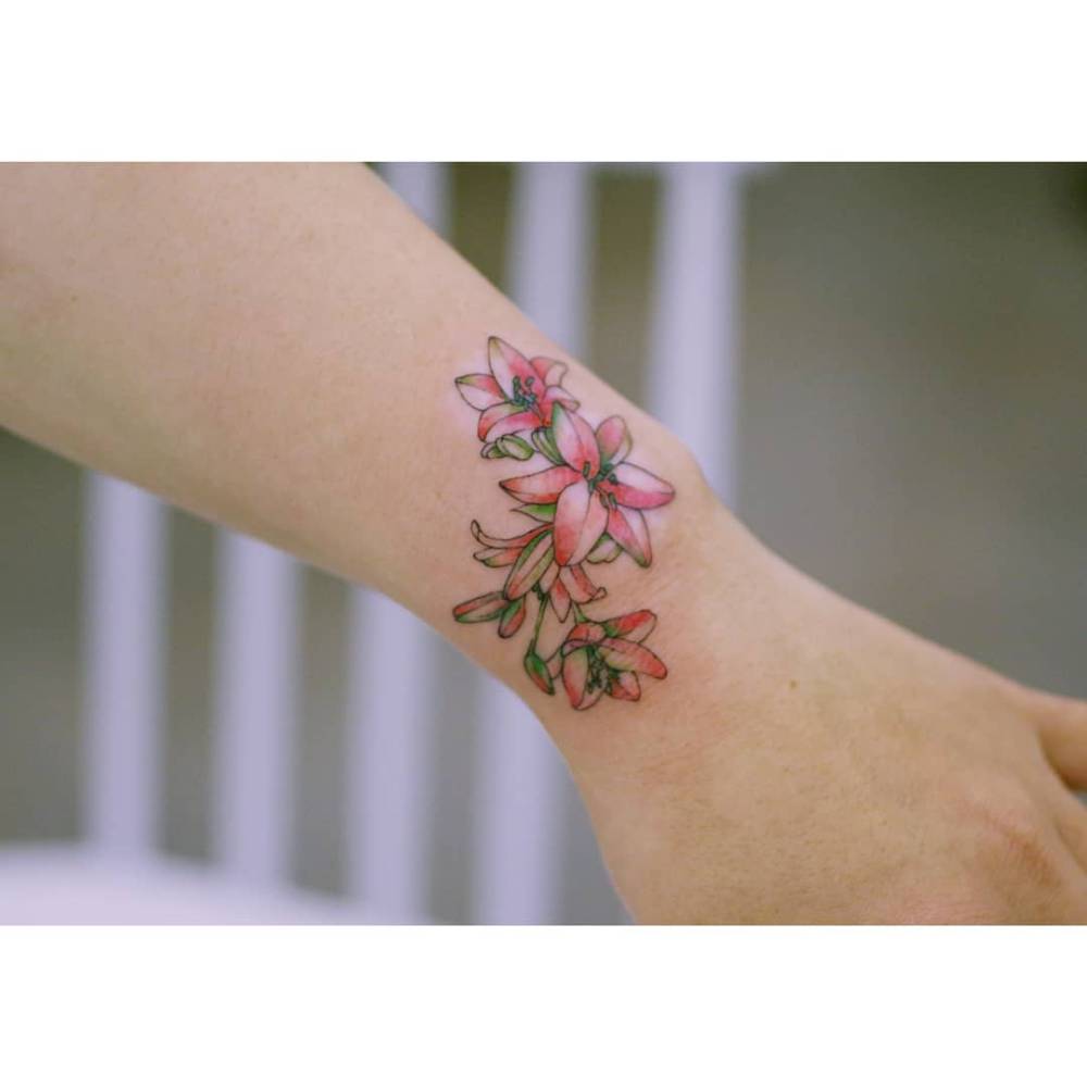 Colorful lilies tattooed on the wrist, illustrative style.