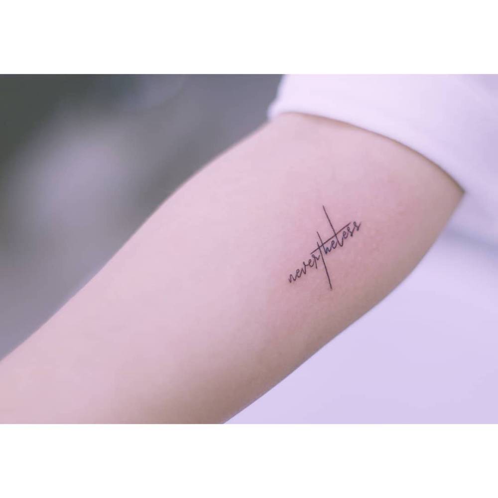 Word "nevertheless" in handwritten font tattooed on the inner forearm.