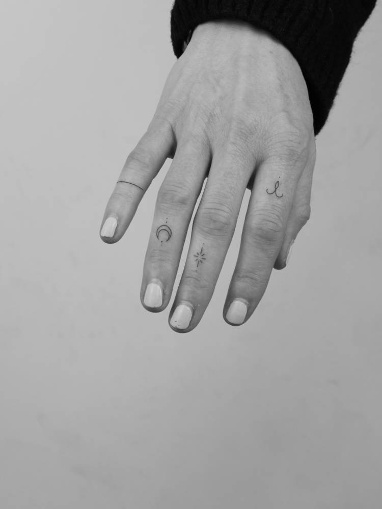 Ring, moon, star and ornament tattooed on the fingers.