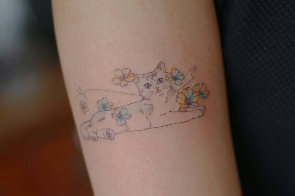 Cute cat tattoo in illustrative style located on the upper arm.