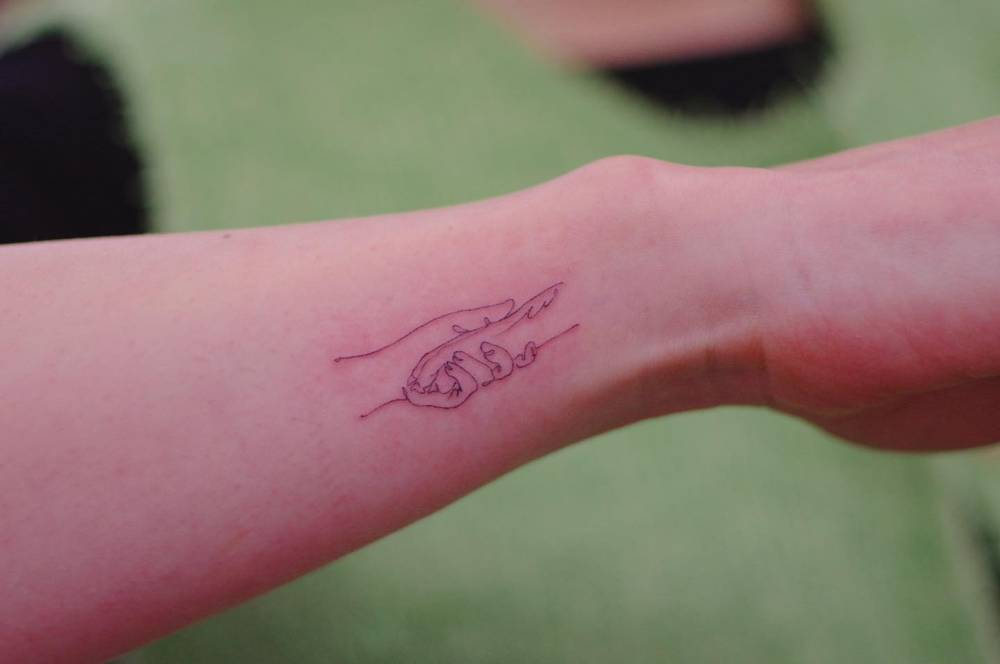 Fine line style hand and paw tattoo located on the wrist.