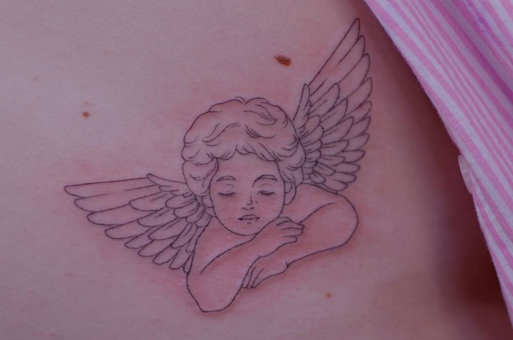 Cherub tattoo in fine line style located on the rib.