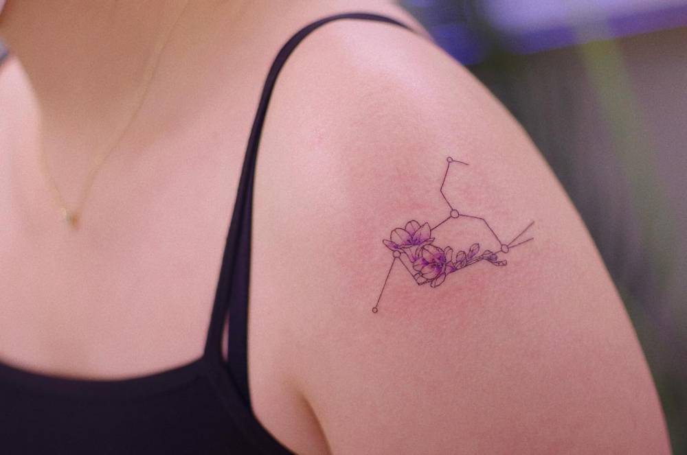 Leo constellation and cherry blossoms tattooed on the shoulder.