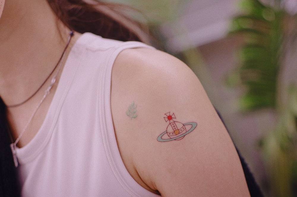 Vivienne Westwood orb in illustrative style tattooed on the upper arm.