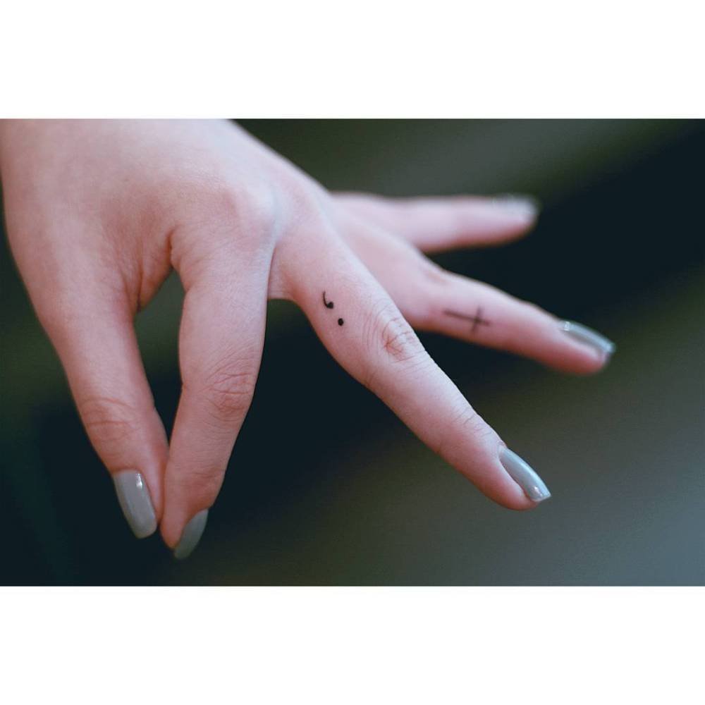 Tiny minimalistic semicolon tattoo placed on the finger.