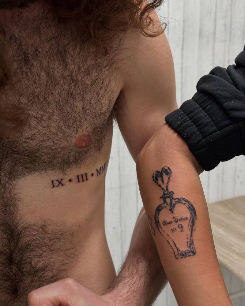 Roman numerals tattoo in serif font located on the rib.