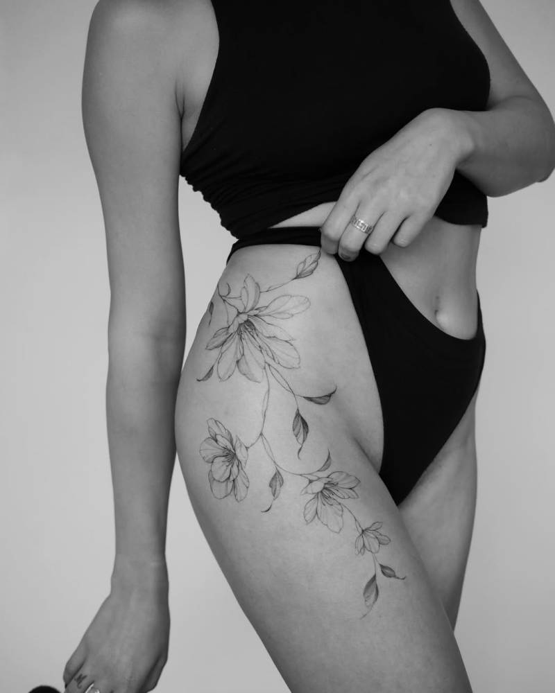 Magnolias tattooed on the hip, done in illustrative style.